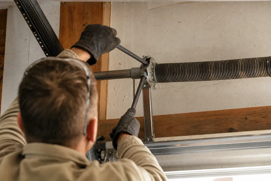 Technician fitting winding bars to a garage door torsion spring